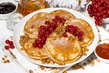 tasty pancakes with berries and honey on a white wooden table