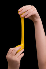 Slime on a black background. Yellow slime in the hands of a girl. Play with mucus.