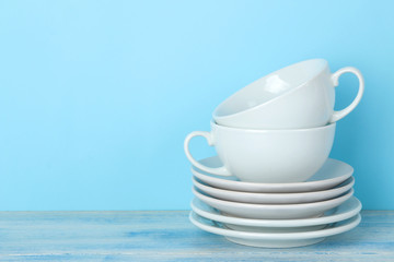 Piles of white ceramic tableware, saucers and cups on a gentle blue background. kitchenware.