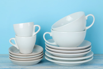 Obraz na płótnie Canvas Piles of white ceramic tableware, saucers and cups on a gentle blue background. kitchenware.