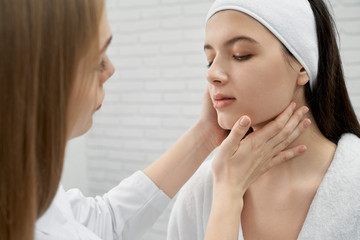 Brunette looking down while female doctor examining skin