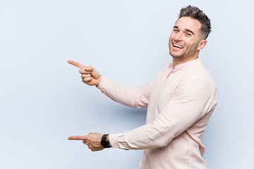 Young handsome cool man excited pointing with forefingers away.