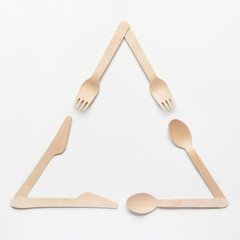 Wooden single use kitchenware in shape of Universal Recycling Symbol on white background. Top view