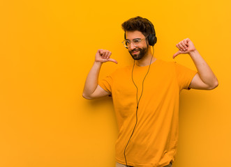 Young man listening to music pointing fingers, example to follow