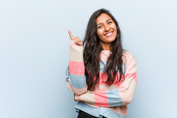 Young fashion indian woman smiling cheerfully pointing with forefinger away.