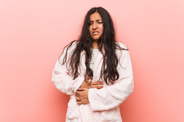 Young indian woman wearing pajama sick, suffering from stomachache, painful disease concept.