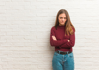 Young cool woman over a bricks wall crossing arms relaxed