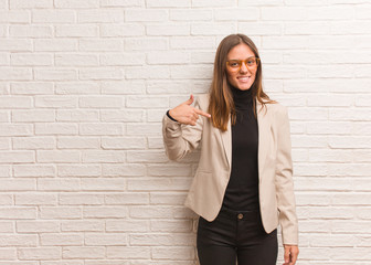 Young pretty business entrepreneur woman person pointing by hand to a shirt copy space, proud and confident