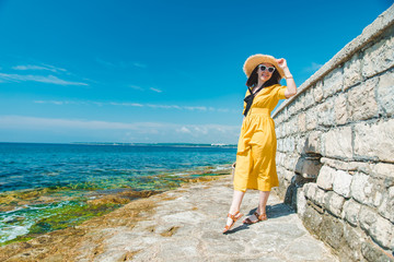 woman in yellow sundress at sea beach in straw hat