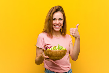 Young healthy woman holding a salad smiling and raising thumb up