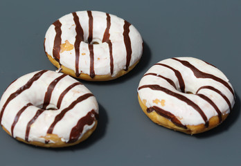 selfmade vanilla donuts on table. The donuts have white glaze with brown chocolate
