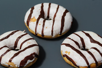 selfmade vanilla donuts on table. The donuts have white glaze with brown chocolate