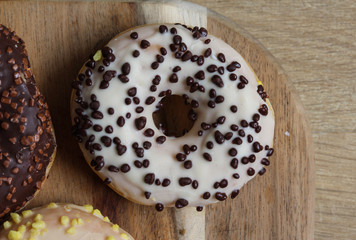 selfmade vanilla donuts on table. The donuts have white glaze with brown chocolate