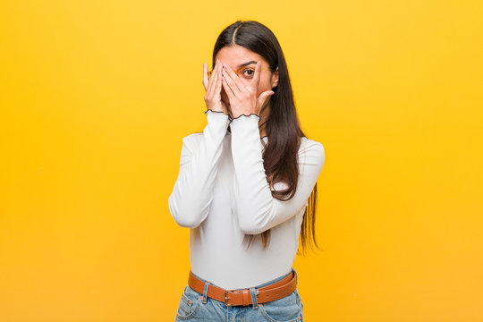 Young pretty arab woman against a yellow background blink through fingers frightened and nervous.