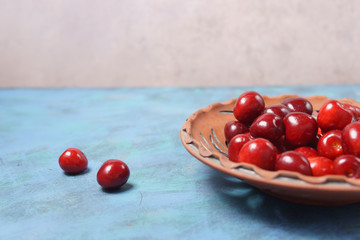 Red sweet cherry in a clay plate on a turquoise table