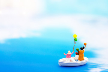 Miniature people: Faminly with balloon on board of sea boat. Summer concept.
