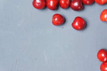Red sweet cherry scattered on a gray background