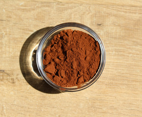 Cocoa powder in a glass bowl on the wooden background