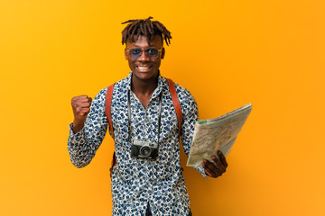 Young rasta black man holding a map cheering carefree and excited. Victory concept.