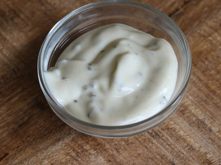 garlic sauce in a glass bowl, on a wooden background