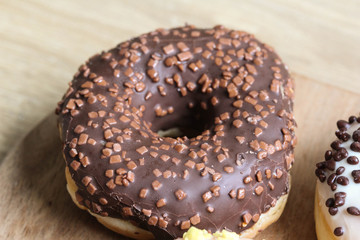 single chocolate donut with sprinkles on a wooden background