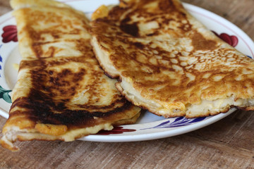 fresh baked pancake with cheese and bacon on plate on wooden background