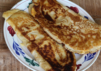 fresh baked pancake with cheese and bacon on plate on wooden background