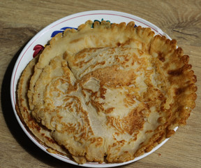 Fresh self baked natural empty pancakes on a white plate on a wooden background