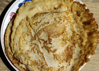 Fresh self baked natural empty pancakes on a white plate on a wooden background