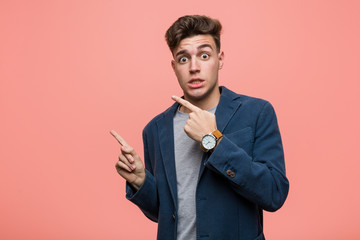 Young business natural man shocked pointing with index fingers to a copy space.