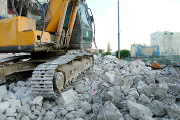 The excavator stands on the destroyed concrete. Excavator caterpillar at a construction site....