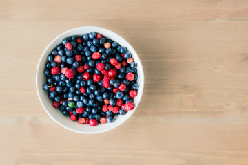 Bowl full of fresh organic blueberries and strawberries, top view