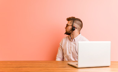 Young man working in a call center gazing left, sideways pose.