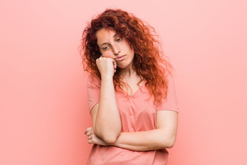 Young natural and authentic redhead woman who feels sad and pensive, looking at copy space.