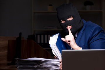 Male employee stealing information in the office night time  
