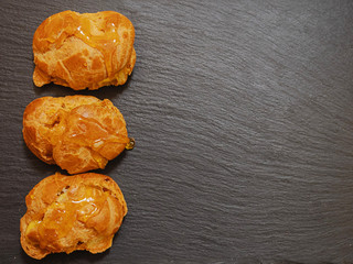 Three eclair covered with sugar sweet syrup on a slate plate, top view, Copy paste.