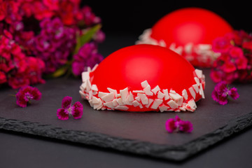 Red strawberry glaze mousse cake, on dark background, closeup. Red cake with mirror glaze.