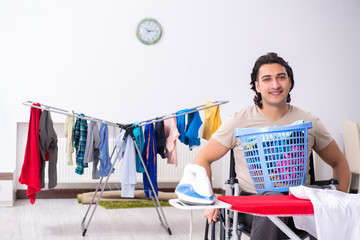 Young man in wheel-chair doing ironing at home 