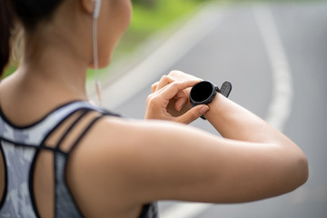 Woman setting up the fitness smart watch for running. Sportswoman checking watch device. Young fitness woman runner checking time from smart watch. 