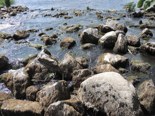 Fototapeta na wymiar Rapid flow of water flows through large rocks