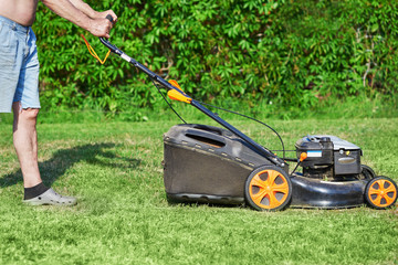 Country works on the personal plot using lawn mower. © Artem