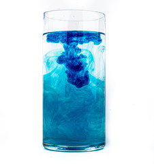 Blue food coloring diffuse in water inside glass with empty copyspace area for slogan or advertising text message, over isolated white background.