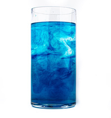 Blue food coloring diffuse in water inside glass with empty copyspace area for slogan or advertising text message, over isolated white background.