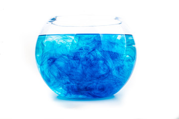 Blue food coloring diffuse in water inside round bowl with empty copyspace area for slogan or advertising text message, over isolated white background.