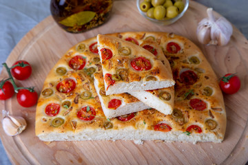 Focaccia with tomatoes and olives. Traditional Italian bread. Homemade baking. Close-up, selective focus.