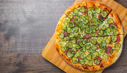 Pizza with Mozzarella cheese, salami, bacon, Tomato sauce, fresh dill, Spices and pickled cucumbers. big dill pizza on wooden table background