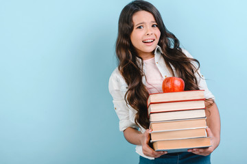 Portrait of unhappy young girl holding stack of books with apple on it. Back to school. - Copyspace