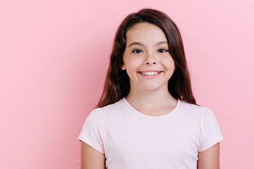 Fototapeta premium Closeup portrait of a happy girl over pink studio background- Image