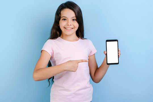 Smiling girl holding a smartphone and pointing to screen - Mockup image of white empty blank screen of phone