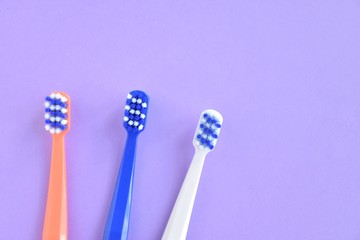Colorful toothbrushes with selective focus on blurred purple background. Dental tools for daily teeth protection. Multicolored plastic toothbrush with bright bristles with soft focus. Oral hygiene 